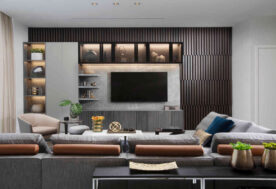 A Neutral Living Room With Blue And Red-orange Hues, TV Feature Wall With Storage, And Wall Panels In A Luxe Waterfront Condo.