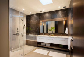 A Bathroom Design Featuring Black Marble Wall Tile, A Double Vanity, And A Walk-in Shower.