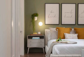 A Neutral Bedroom Design Adorned With Green And Orange Hues And Greenery.