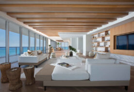 White And Natural Living Room Design Showcasing Wood Ceiling Beams Harmonized With Ocean Views.