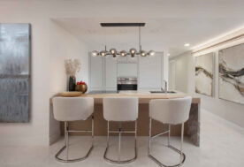 A Kitchen Design With An Island Layout Adorned With Glass Pendant Lighting.