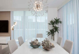 A Dining Room Design In Soft, Neutral Tones Adorned With A Pendant Lighting Fixture.