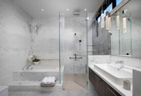 Master Bathroom Design Featuring White Marble Walls, Walk-in Shower, And Built-in Bathtub.