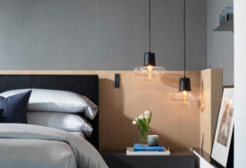 A Dark Neutral Bedroom Featuring Glass Pendant Lighting And Carpentry In A Contemporary Oceanfront Retreat Home.