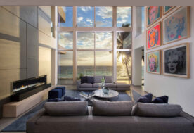 A Contemporary Oceanfront Retreat Home Featuring A Living Room With A Built-in Fireplace, Pop-art Decor, And An Ocean View.