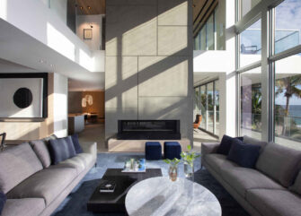 A Contemporary Oceanfront Retreat Home Featuring A Living Room With A Built-in Fireplace.