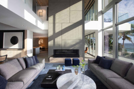 A Contemporary Oceanfront Retreat Home Featuring A Living Room With A Built-in Fireplace.