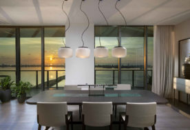 Modern-Asian Inspired Penthouse Design Showcasing A Dining Area Adorned With Pendant Lighting, Complemented By Cityscape And Waterfront Views By DKOR Interiors.