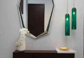 An Entry Foyer Vignette With A Pair Of Emerald Pendants And An Emerald Ottoman Play Off The Gem-Shaped Mirror