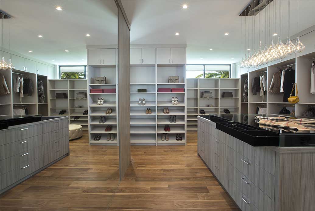 A luxury walk-in closet design featuring a mirrored wall, dresser, and shoe compartment.