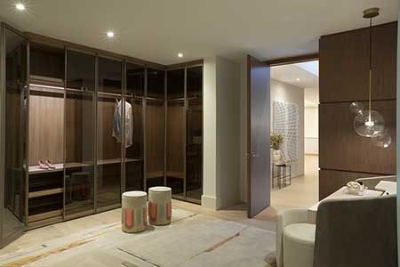 A luxury closet design featuring a wardrobe, ottomans, and complemented by a glass pendant light.