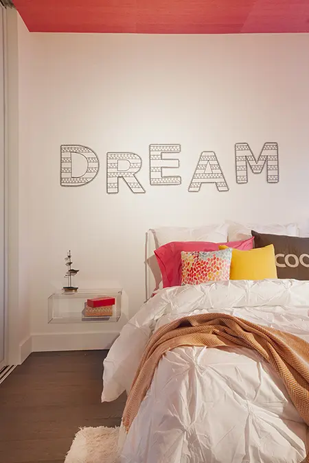 A kids' girl's bedroom design with a dream sign on the wall