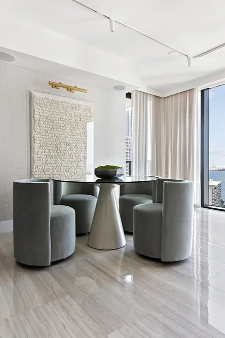 Round table dining room area in a Brickell apartment with neutral art.