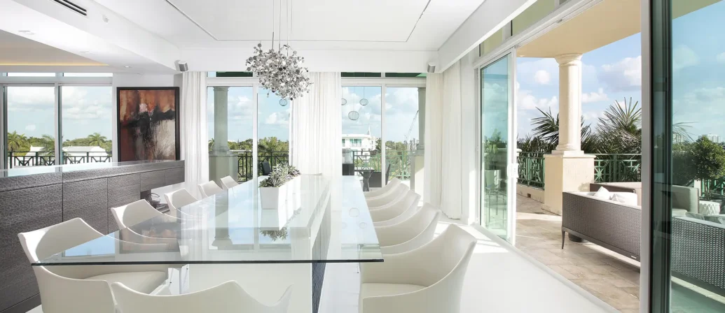 White Dining Room Design With Glass Table And Floor To Ceiling Windows