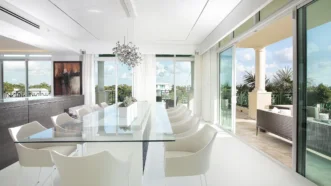 White Dining Room Design With Glass Table And Floor To Ceiling Windows